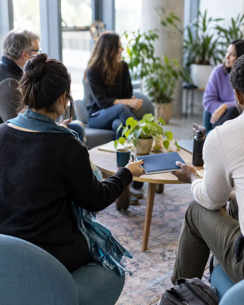 Adult members of a university community discussing around a table.